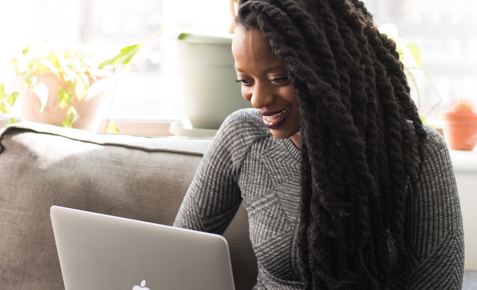 A person smiling while working on a laptop at home